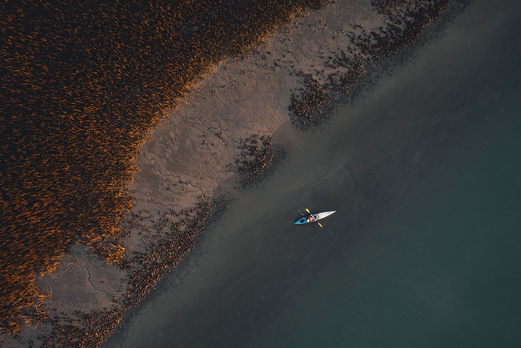 overhead drone shot of a solo person sea kayaking on a trip along the South Carolina beach