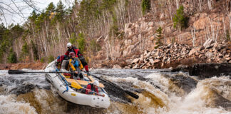 a group of whitewater rafters go over some rapids on a paddling dream trip