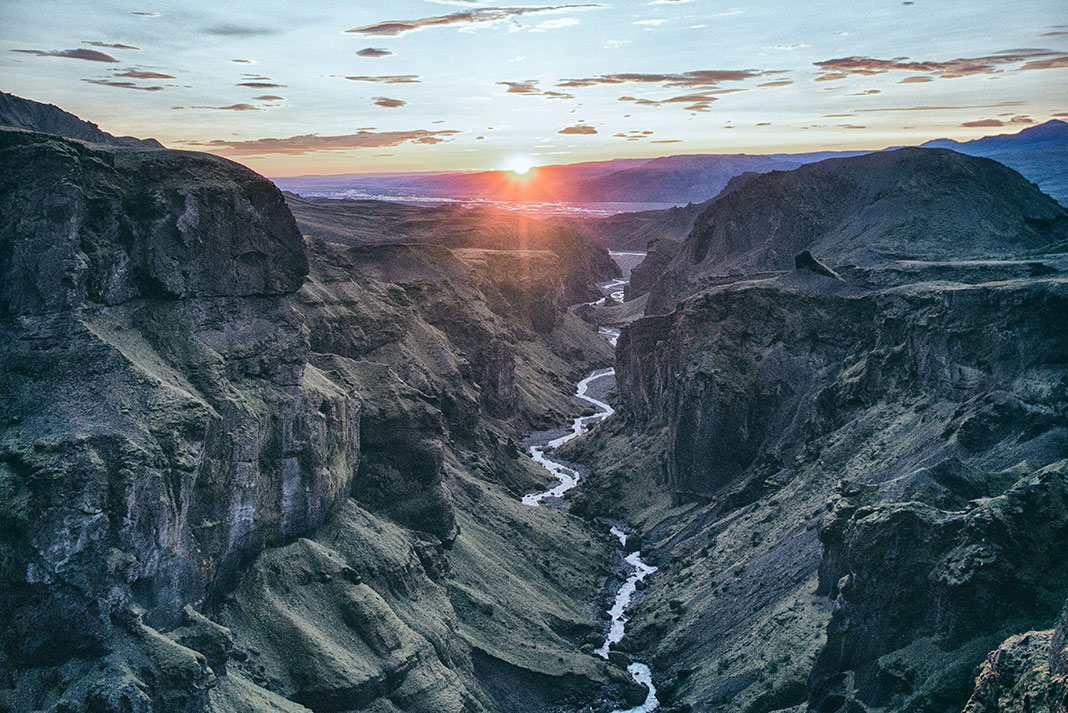 sun sets over a river canyon