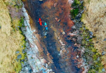 overhead photo of red and blue kayaks running a rocky river