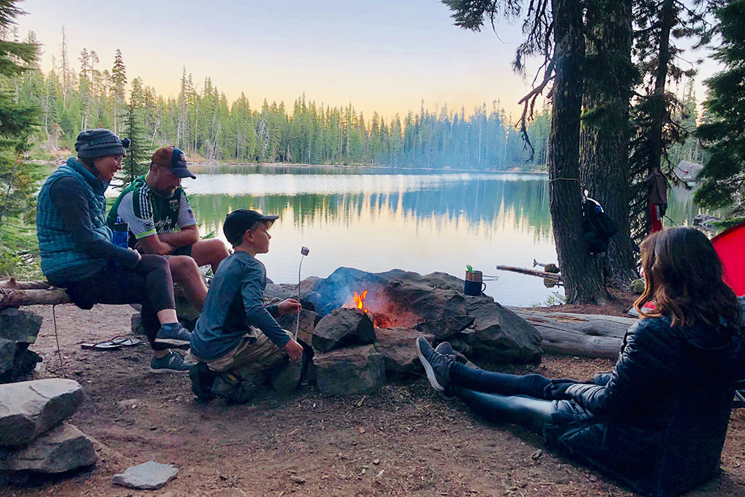 a family toasts marshmallows around a campfire on a camping trip
