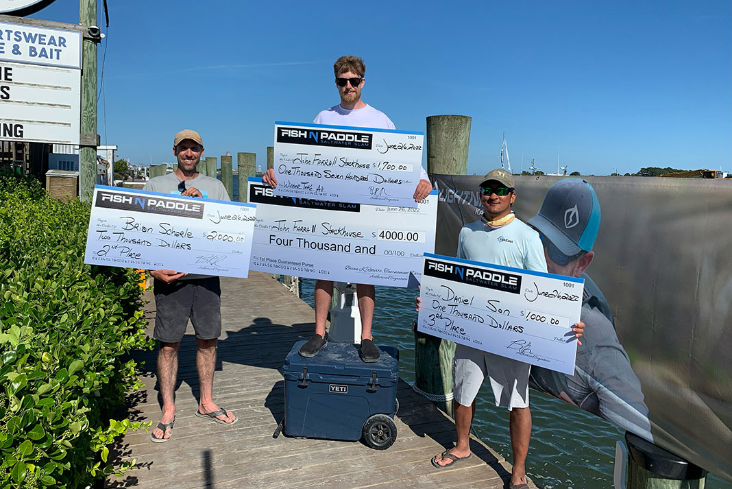 three tournament anglers pose with their novelty winners checks