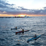 Zero To Hero: How Rookies Tackled The Infamous Bass Strait three sea kayakers paddle across the Bass Strait at dusk