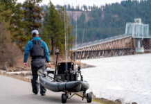 angler pulls his fishing kayak on a cart toward a bridge