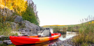 Orange and yellow sit-on-top kayak in shallow water.