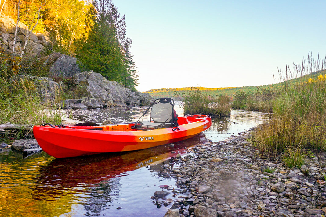 Orange and yellow sit-on-top kayak in shallow water.