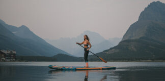 Woman on inflatable paddleboard on lake with mountain in background