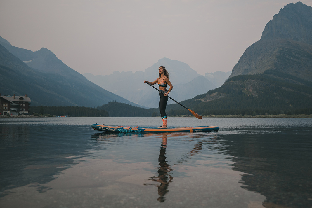Woman on inflatable paddleboard on lake with mountain in background