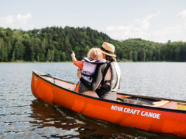 Woman and little girl sitting in bow of red canoe.