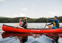Family paddling red canoe across a lake.