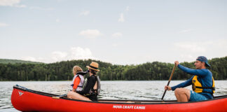 Family paddling red canoe across a lake.
