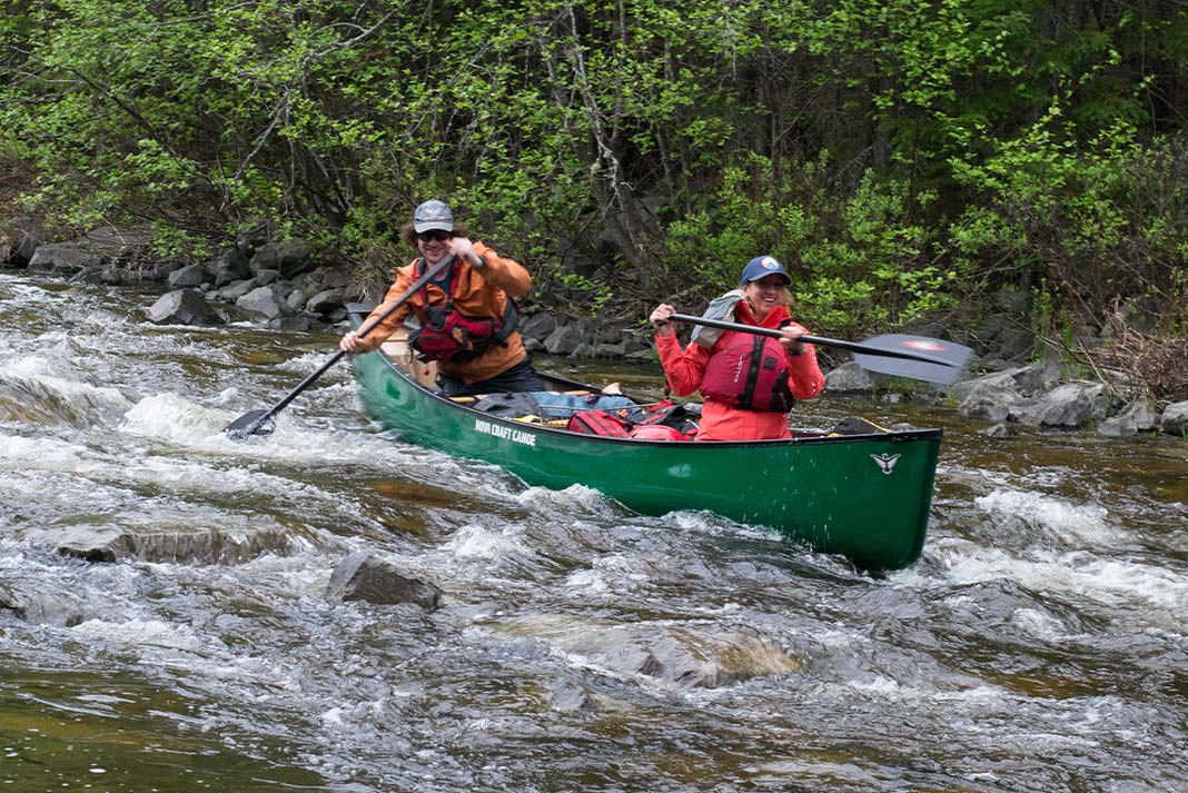 Man and woman in green canoe going through swifts