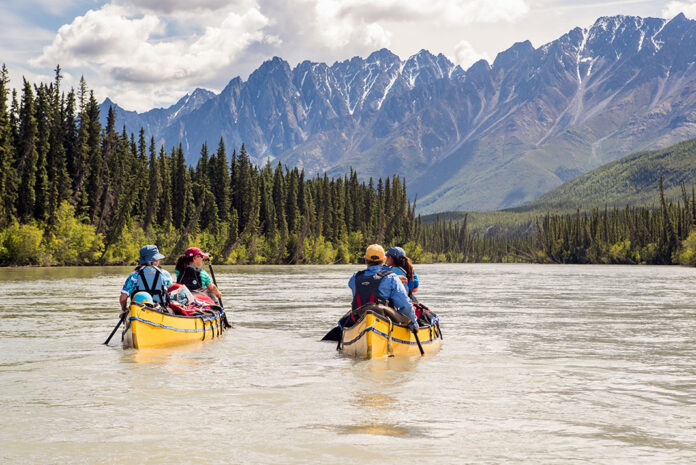 two yellow canoes paddle along the Nahanni River