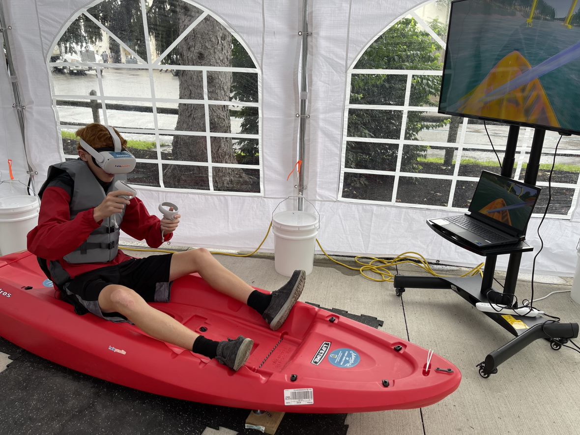 Child using a VR headset on a red sit-on-top kayak.