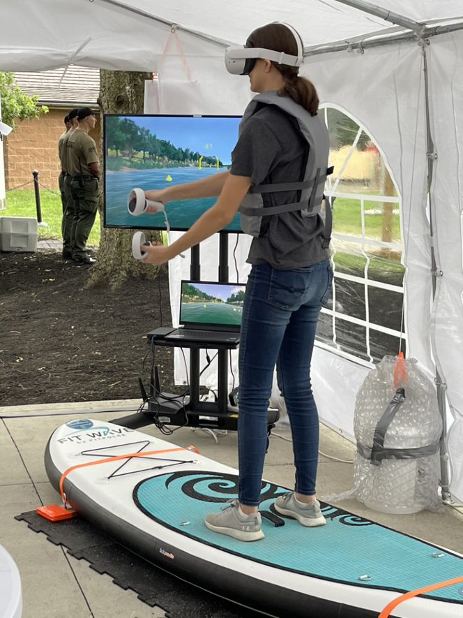 Young girl using a VR headset while standing on a paddleboard.