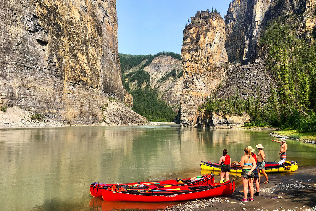 a group of expedition canoeists stop and scout the Nahanni River