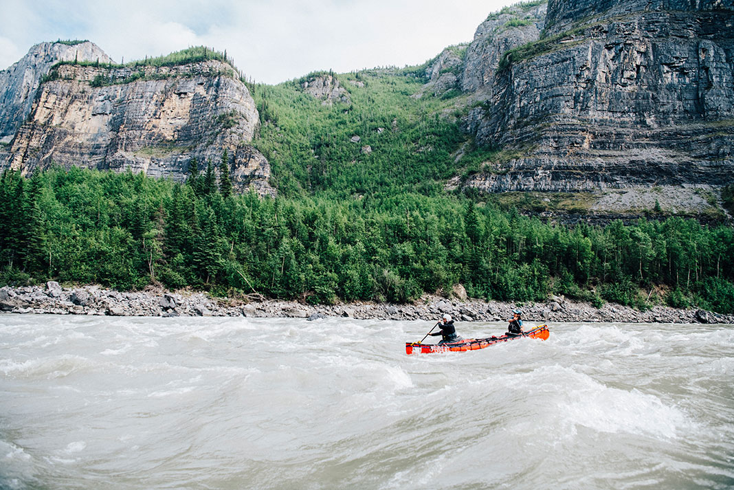 two people paddle a red canoes on the Nahanni River