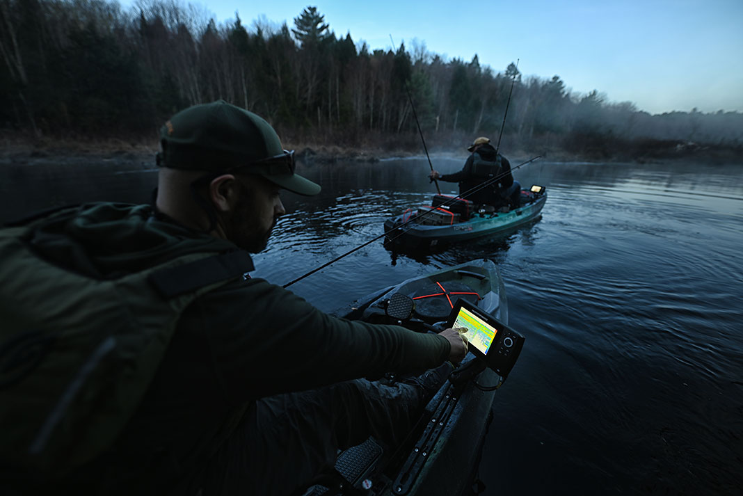 two kayak anglers fish in the dusk with electronics like fish finders