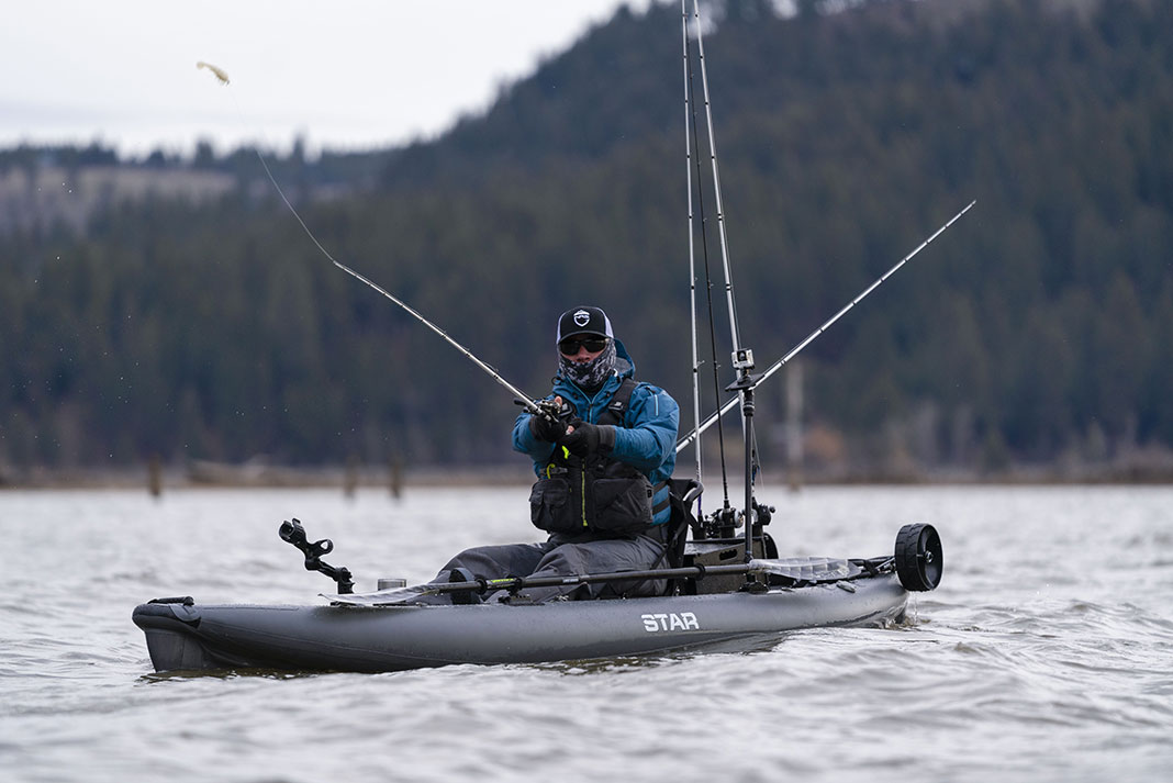kayak angler with face covering casts a white soft plastic bait while fishing in Idaho, United States