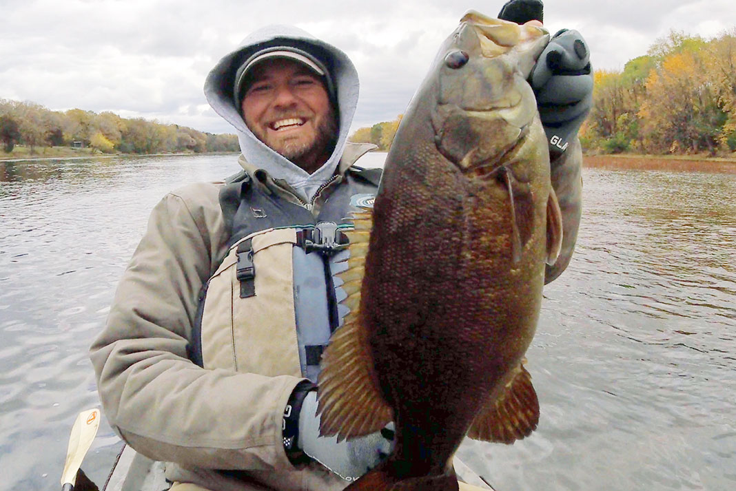 man in winter fishing gear holds up large fish caught in Minnesota, United States