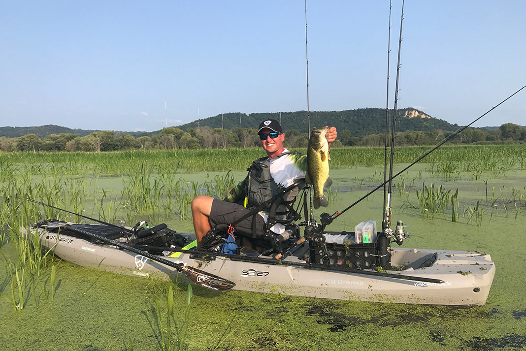 male kayak angler holds up a bass caught on Wisconsin's grassy flats