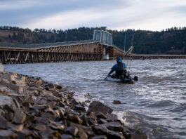 United States kayak angler goes fishing near bridge on cloudy day