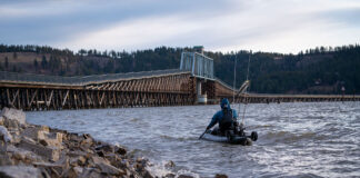 United States kayak angler goes fishing near bridge on cloudy day
