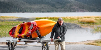 man pulls two fishing kayaks on a tandem trailer