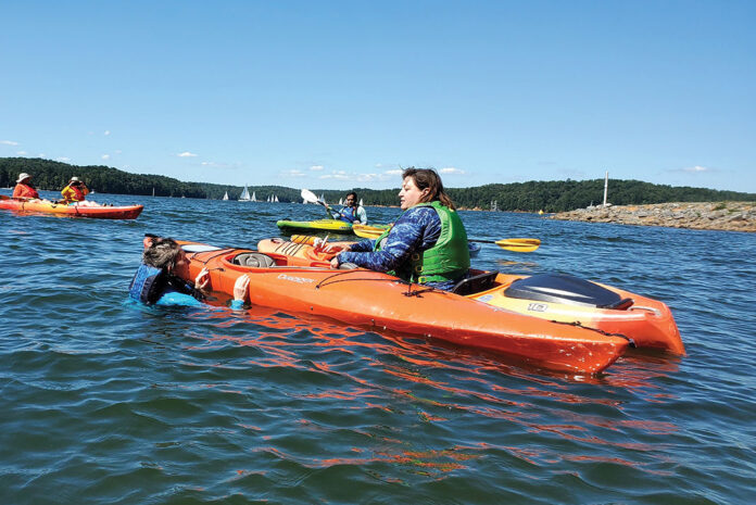 woman trains recreational kayakers on rescue techniques