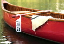 a do not disturb sign is hung from a paddle over a canoe suggesting someone is planning to have sex in the canoe