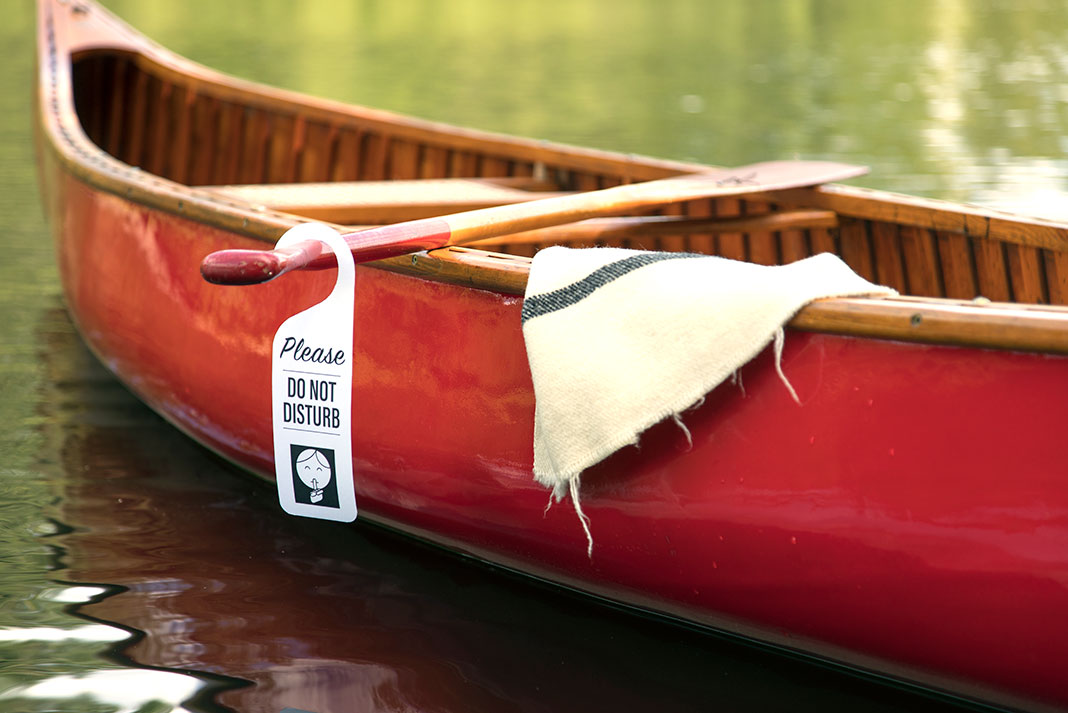 a do not disturb sign is hung from a paddle over a canoe suggesting someone is planning to have sex in the canoe