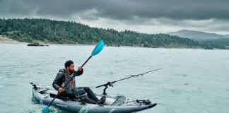 man paddles an Aquaglide fishing kayak on a cloudy day