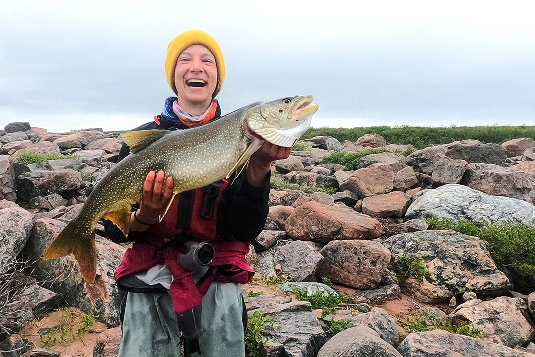 woman holds large fish caught while on expedition in Canada's Arctic