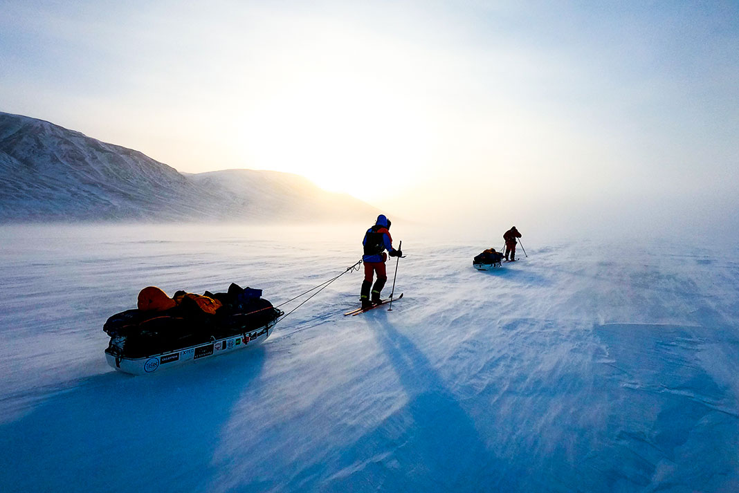 expedition members ski across the Arctic tundra