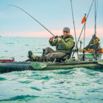 Best Ocean Fishing Kayaks For 2026 man reels in fish from Old Town Sportsman BigWater PDL 132
