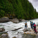 5 Top Women’s Drysuits Go Head-To-Head a group of female whitewater paddlers scout a river while wearing womens drysuits
