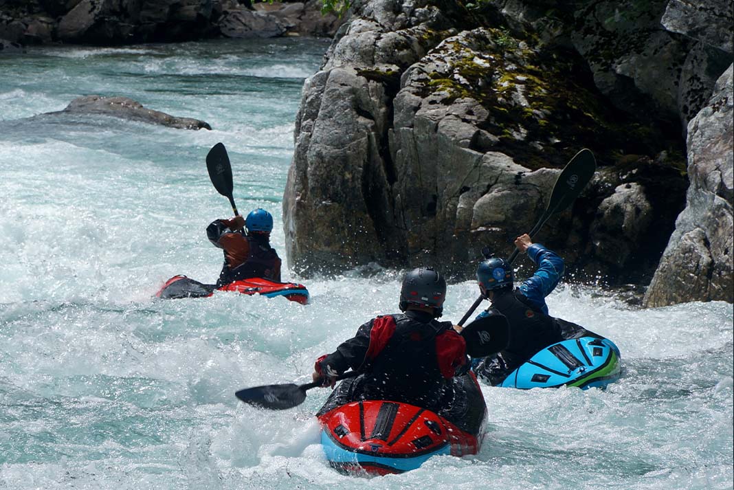 Three paddlers going down a rapid.