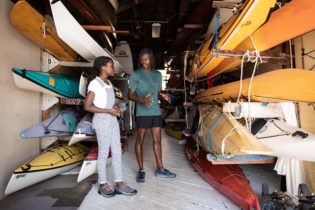 Man and woman stand in room surrounded by kayaks on racks