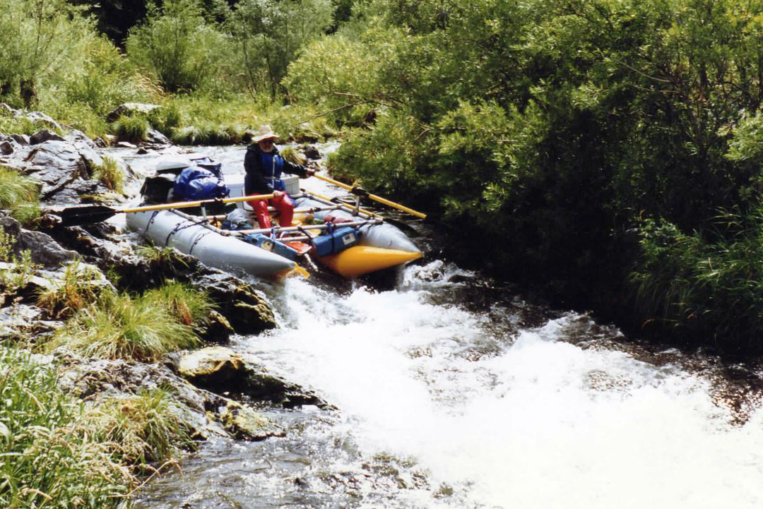 Bill Parks paddles a whitewater raft down a small creek