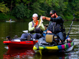 one man photographs a bass caught by another from Jackson tandem kayaks