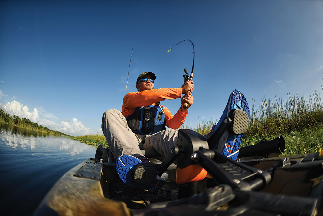 Man sits and casts from a pedal fishing kayak