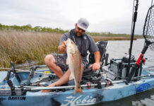 man holds up a redfish caught from his Hobie kayak with new fishing lures