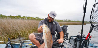 man holds up a redfish caught from his Hobie kayak with new fishing lures