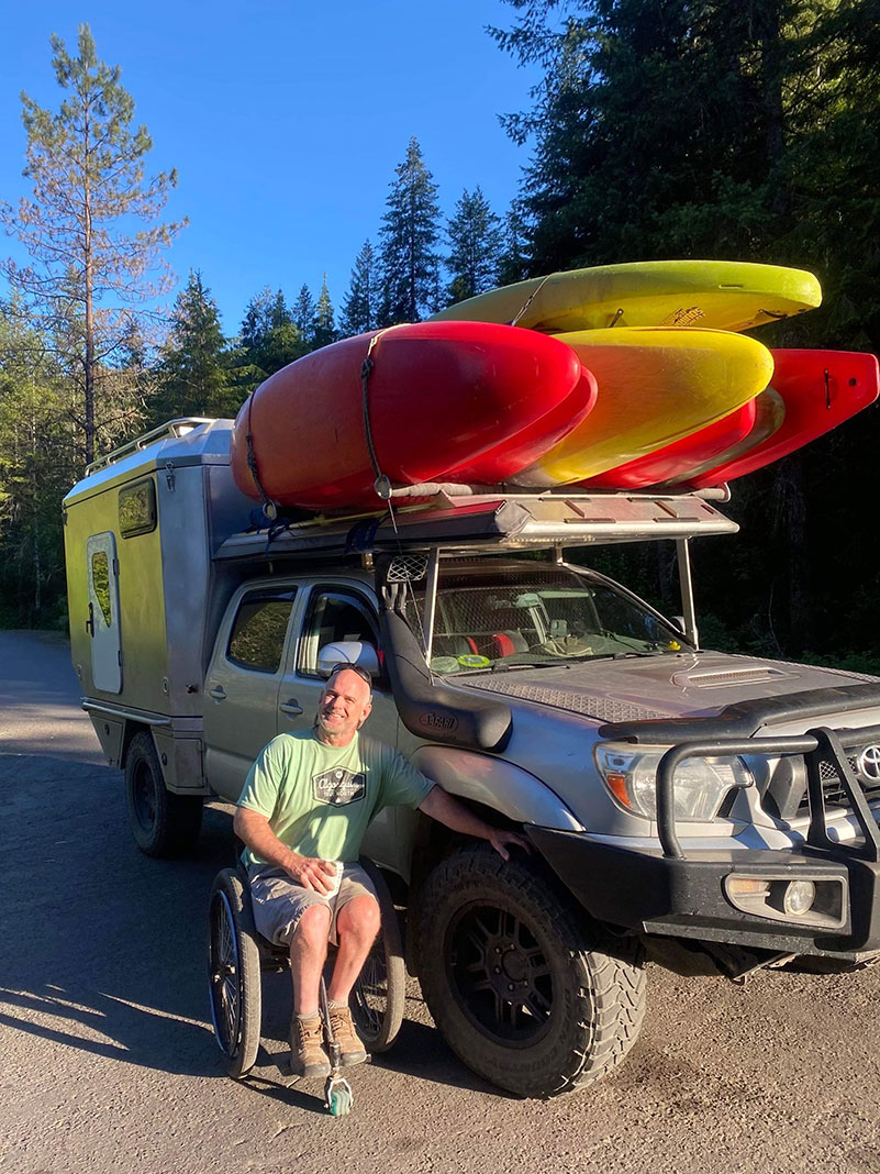 Dave Calver poses beside his custom pickup truck and kayaks