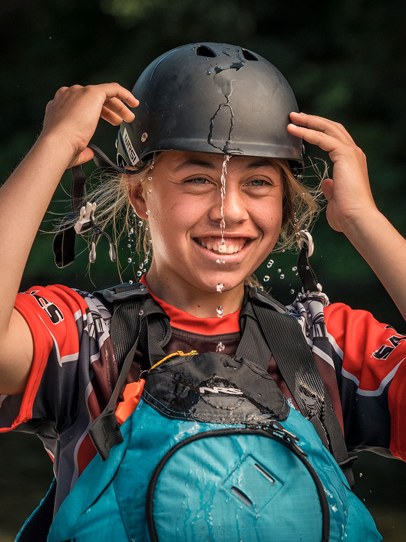 smiling girl whitewater paddler puts on her helmet