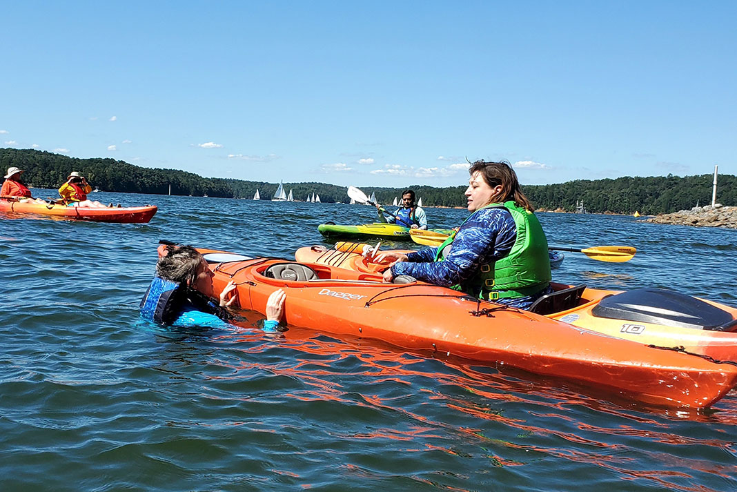 woman teaches a kayak rescue course to some beginner kayakers