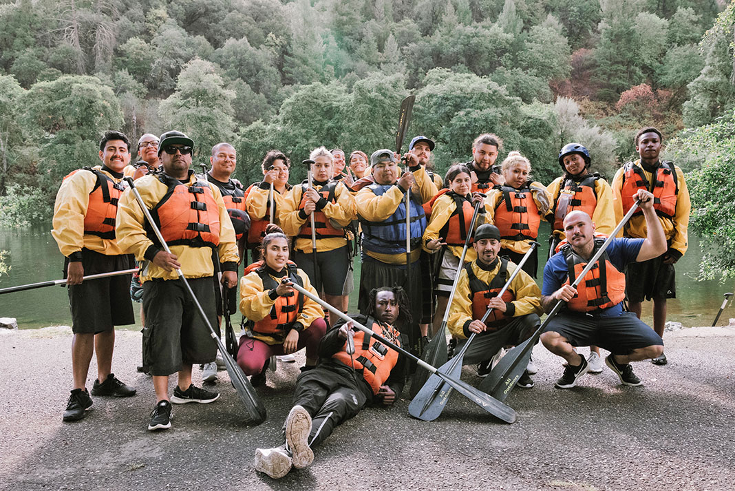 a group of ex-gang members pose in paddling gear after taking part in a beginners paddling program