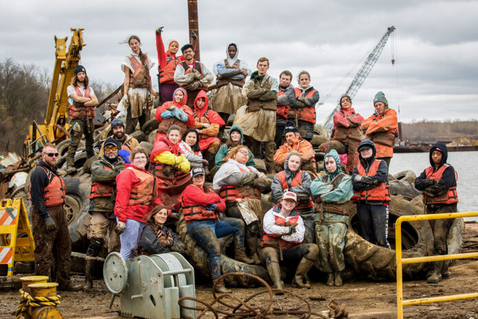 a group of people with Living Lands And Waters pose with muddy debris they have cleared from the water