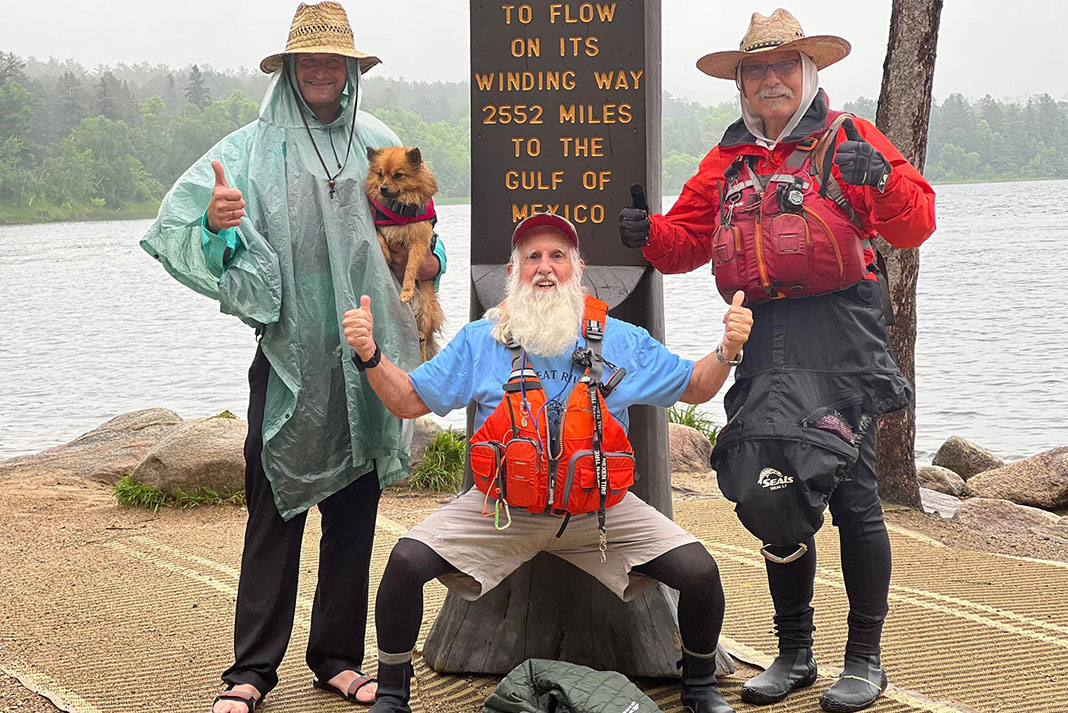 Dale Sanders and paddling friends pose in front of a waymarker sign