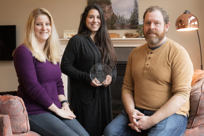 Three people pose with award